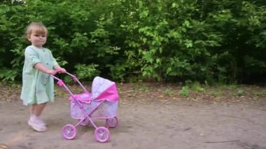 Küçük kız oyuncağıyla yaz parkında yürüyor.