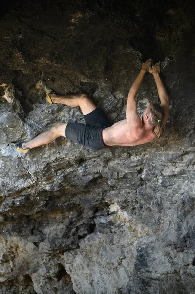 Junger männlicher Kletterer beim Bouldern einer Felswand in einer Höhle — Stockfoto