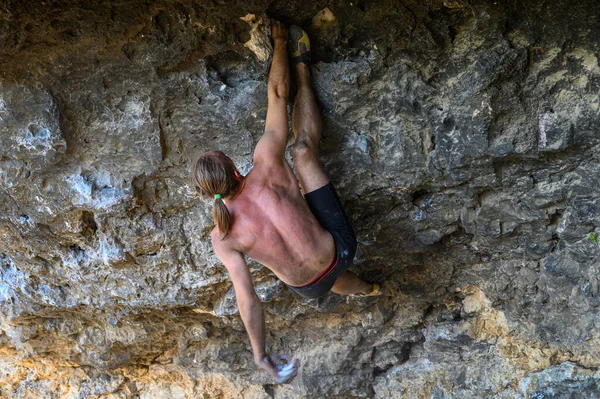 Young male climber bouldering a rock wall in a cave — Stock Photo, Image