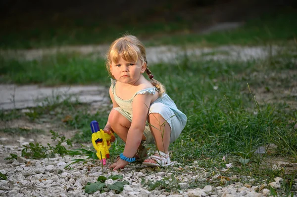 Klein blond meisje met een waterpistool — Stockfoto