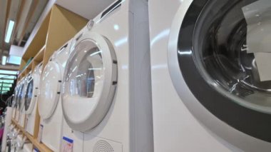 Ev aletleri mağazasında sıra sıra çamaşır ve kurutma makineleri var.