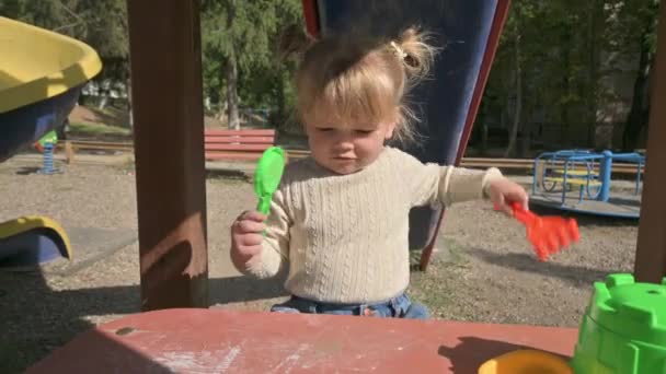 Menina loira brincando com ancinho e peneira na mesa no playground — Vídeo de Stock