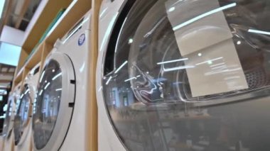 Ev aletleri mağazasında sıra sıra çamaşır ve kurutma makineleri var.