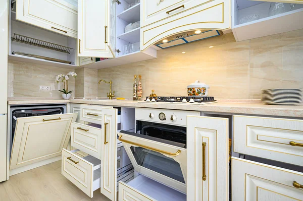 Mutfakta bej renkli mobilyalar, tüm kapılar açık.