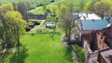 Letonya, Avrupa 'daki Havadan Yok Edilmiş Odzienas Şatosu Güzel Güneşli bir Bahar Günü, Kırsal kesimde Uyum içinde Seyahat kavramı. Antik Kale 'nin ayrıntıları. Kuledeki Leylek Yuvası