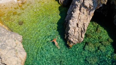Bikini 'deki Güzel Genç Kadın, Hırvatistan' ın Stara Baska Sahili Krk Adası 'nda yüzüyor. Akdeniz Yazı. Yukarıdan havadan ateş edildi. Mavi Deniz Kayalık Dağlar ve Sahil Kıyısı Açık Mavi Suyla