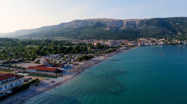 Krk Adası, Hırvatistan Adriyatik Denizi, Vela Plaza Sahili, Dağlar ve Kamp Kenti manzaralı Baska Sahili Açık Turkuaz Suyu, Marina Tekneleri, Şehir Caddesi, Güneşli Yaz Günbatımı Hava Manzarası