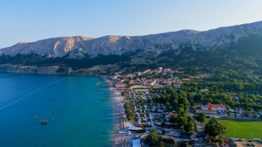 Krk Adası, Hırvatistan Adriyatik Denizi, Vela Plaza Sahili, Dağlar ve Kamp Kenti manzaralı Baska Sahili Açık Turkuaz Suyu, Marina Tekneleri, Şehir Caddesi, Güneşli Yaz Günbatımı Hava Manzarası