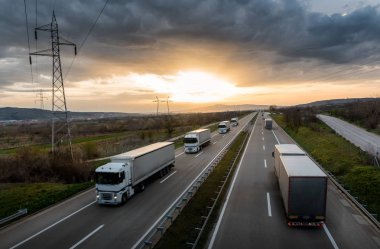 Karavan veya çizgi günbatımında bir ülke karayolu üzerinde beyaz kamyon konvoyu