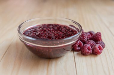 Ev yapımı ahududu jam taze olgun organik ahududu ahşap bir masa üzerinde bir cam kase