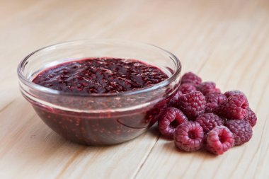 Ev yapımı ahududu jam taze olgun organik ahududu ahşap bir masa üzerinde bir cam kase