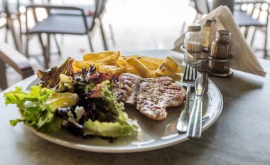 Kızarmış patates, buzdağı salatası ve sebze'de bir tabloda bir Akdeniz restoran ızgara tavuk fileto