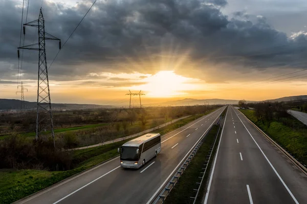 Gün batımı ile yalnız kırsal otoyol seyahat eden otobüs arkasında