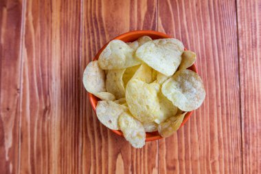 Ahşap arka plan üzerine bir kase gevrek patates cipsi