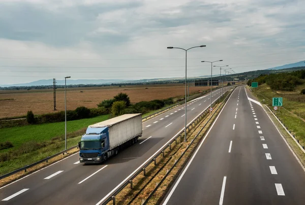 Blauer Lkw Fährt Auf Asphaltierter Autobahn Mit Hochmastbeleuchtung Einer Weidelandschaft — Stockfoto
