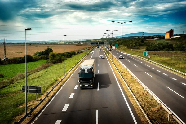 Karayolu trafik pastoral manzara ile bulutlu bir günde düz bir yolda