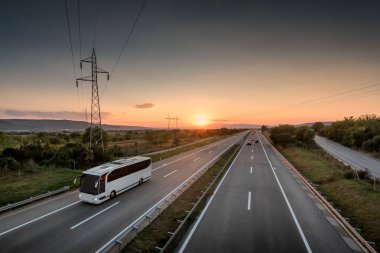 Güzel gün batımı ile yalnız kırsal otoyol seyahat eden otobüs arkasında