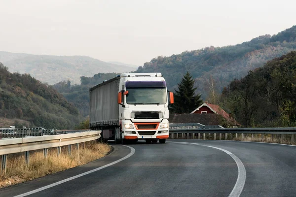Beyaz kamyon taşıyıcı bir dağ yolda