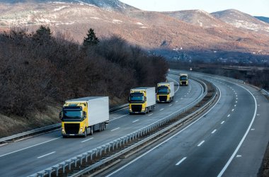 Dramatik bir gökyüzü altında ülke karayolu üzerinde Sarı kamyon karavan veya konvoy