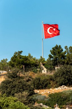Tepenin üstünde açık mavi gökyüzüne karşı Türkiye 'nin ulusal bayrağı