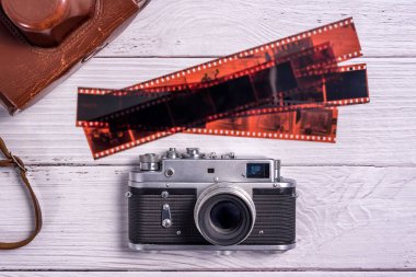 Beyaz ahşap masanın üzerinde deri çantalı ve fotografik filmli klasik film mesafe bulucu kamera. Yukarıdan manzara. Eski teknoloji