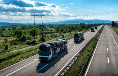 Araba taşıyıcı karavan konvoyu, araba taşıyıcısı, araba taşıyıcısı, güzel bir yolda, güneşli bir yaz gününde. Yeni araba taşımacılığı