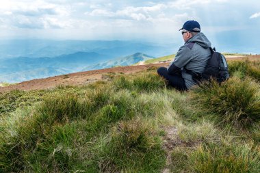 Sırt çantalı bir adam dağın tepesinde. Dağ manzarası. Dağ katmanları manzarası. Çayırlar ve dağların manzarası. Mavi dağ katmanları. Dağların Tepesi