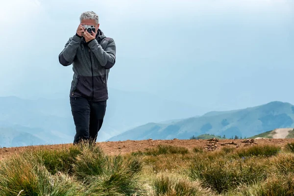 Photographer with old analog camera at a Mountain top. Mountain landscape view. Mountain layers landscape. Meadows and mountains landscape. Blue mountains layers landscape. Top of the Mountains