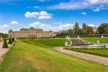 Viyana 'daki tarihi Belvedere Sarayı' nda su, yeşil bahçe ve mavi gökyüzü yansıyor..