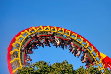 Sürücüler, canlı kırmızı ve sarı bir lunapark treninde heyecan verici bir ters takla atarlar.