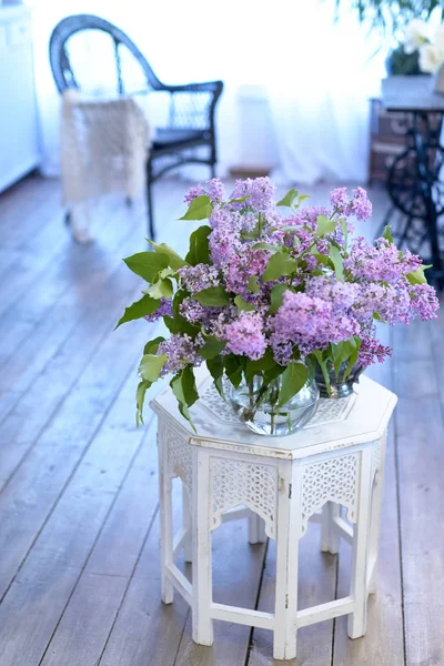 Bouquet of lilac in a glass vase./Bouquet of lilac in a glass vase. Interior with chair.