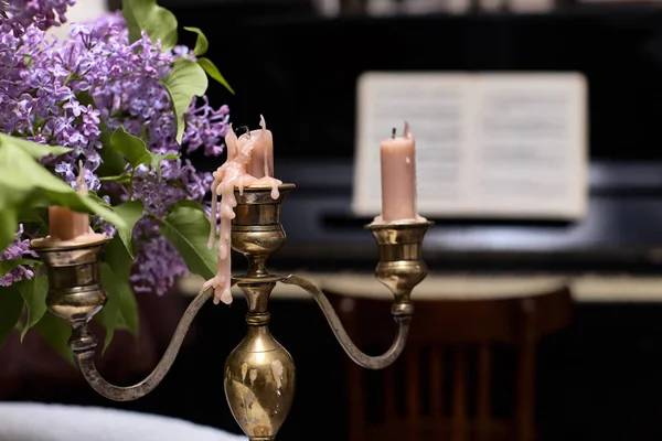 Mumlu şamdan ve bir demet leylak. Bir demet leylağın arka planında mumlar olan şamdan..