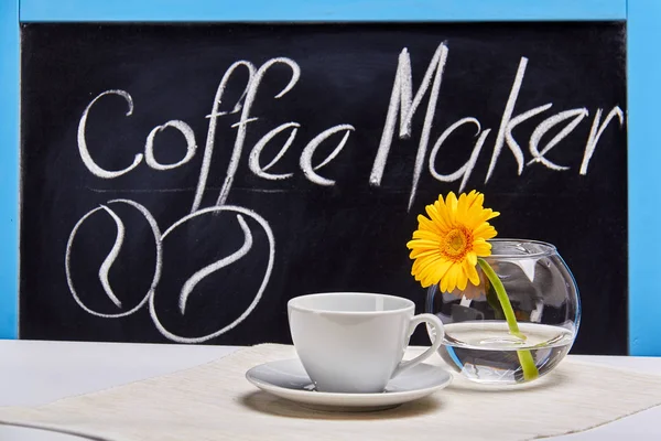 Cup of coffee and bowl of gerberas.