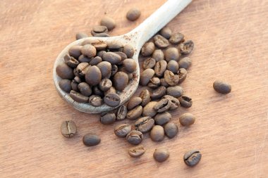Bir tahta kaşık kahve çekirdekleri yığını. Kavrulmuş kahve çekirdekleri.