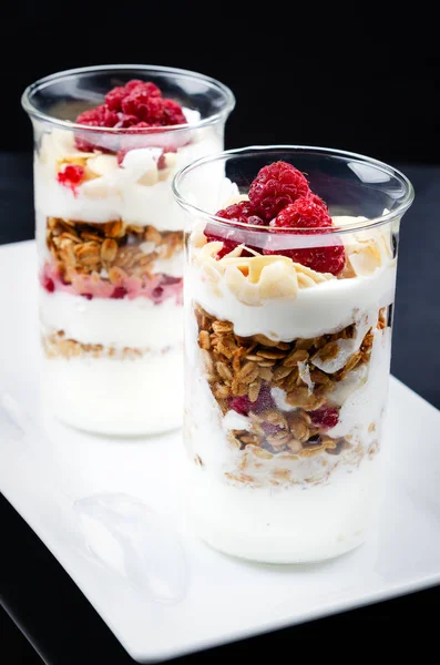 Portioned Granola with Greek Yogurt and Raspberries. Served in a glass. Restaurant feed.