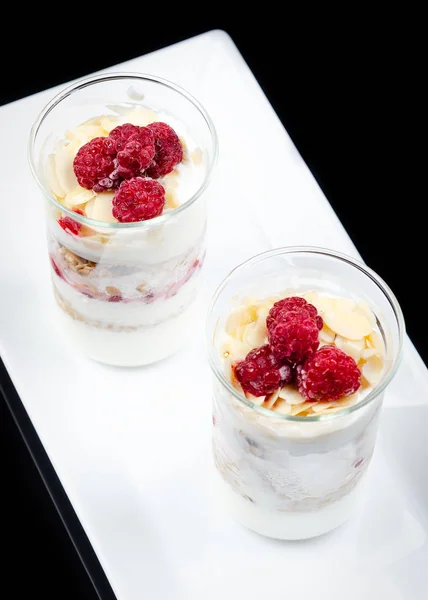 Portioned Granola with Greek Yogurt and Raspberries. Served in a glass. Restaurant feed.