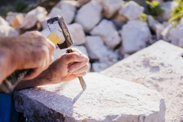 Stone carver working with hammer and chisel