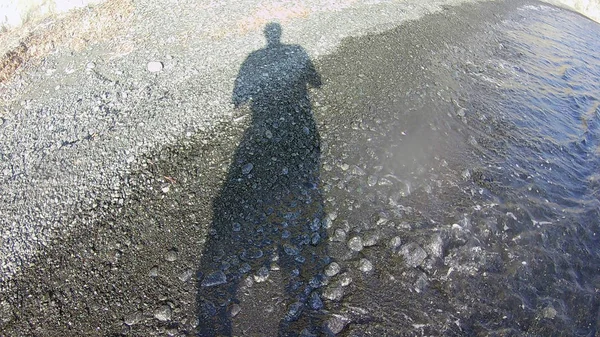 human shadow on the beach stones