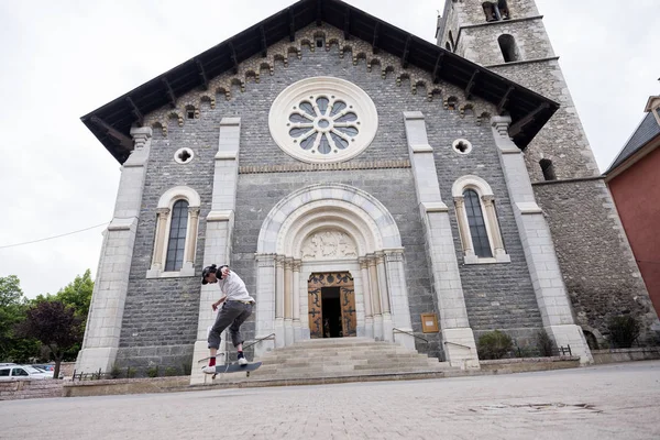 Boy stunts on skate board in front of catholic church in barcelonette — Stock Photo, Image