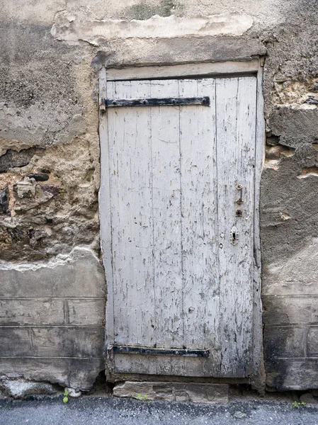 Very old white painted peeling grungy door in ancient wall of medieval house — Stock Photo, Image