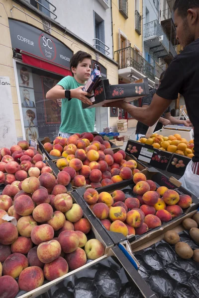 Fiú értékesíti, őszibarack- és más gyümölcsök, szabadtéri piacon briancon, a francia haute provence-ban — Stock Fotó
