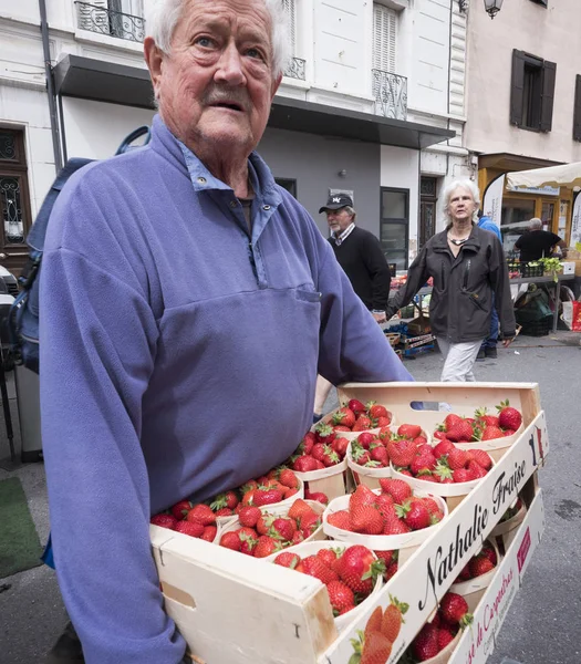 Man draagt zaak vol aardbeien op open lucht markt in de Franse stad van briancon in Franse haute provence — Stockfoto