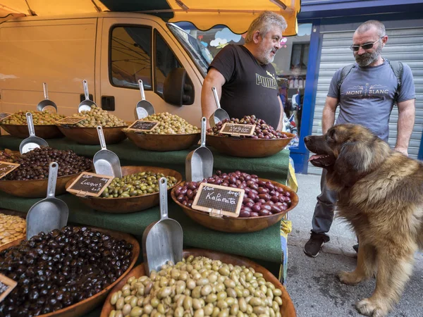 Vendedor de azeitona e homem com grande conversa cão no mercado ao ar livre na cidade francesa de briancon — Fotografia de Stock