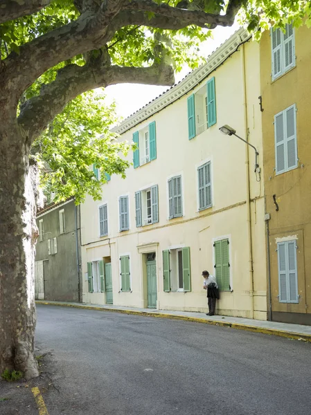 Uomo indossa cappello e si appoggia contro il muro giallo nella vecchia città medievale provenienza francese di bargemon — Foto Stock