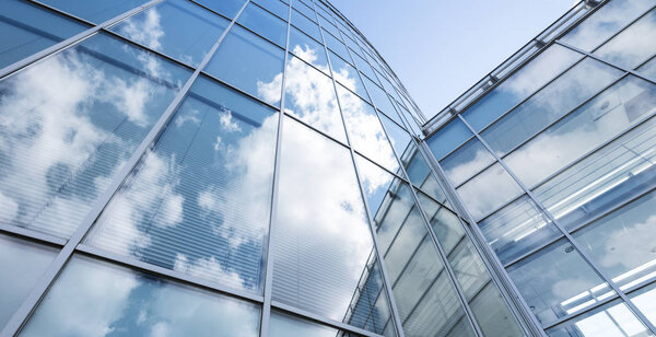 Modern blue glass and metal office architecture facade reflects clouds and blue sky
