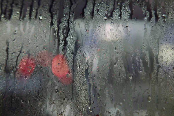 Kırmızı ıslak camdan yağış sırasında görülen ışıklar — Stok fotoğraf