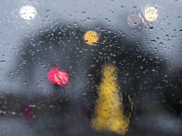 カラフルなライトおよび暗闇の後の車のガラスに土砂降りの中に雨の滴の抽象的なパターン — ストック写真