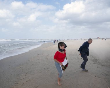 insanlar iskele altında scheveningen plajda yürüyüş ve fırtına sırasında güçlü rüzgar içine yalın