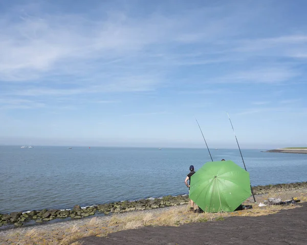 Hommes derrière grand parapluie vert cherchent protection contre le soleil whi — Photo