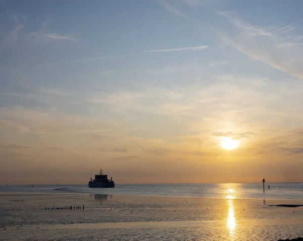 Ferry vanaf Ameland arriveert tijdens zonsondergang in de haven van Holwerd in — Stockfoto